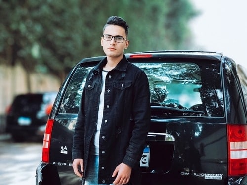 Young man standing beside his car