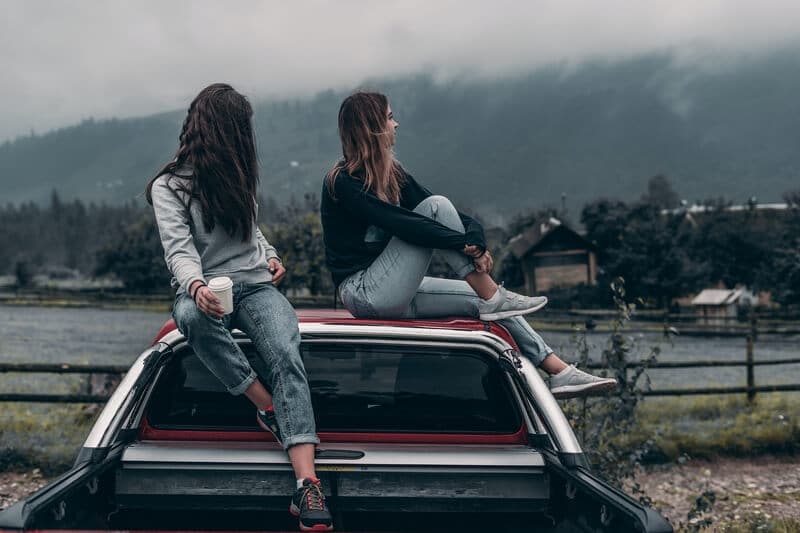 two girls sitting on top of a car
