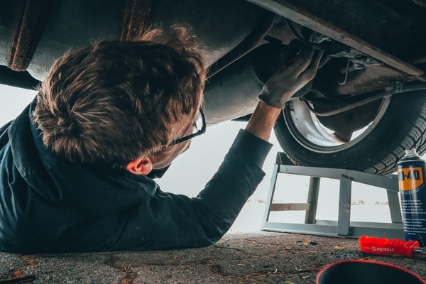 Person under a car doing an oil change